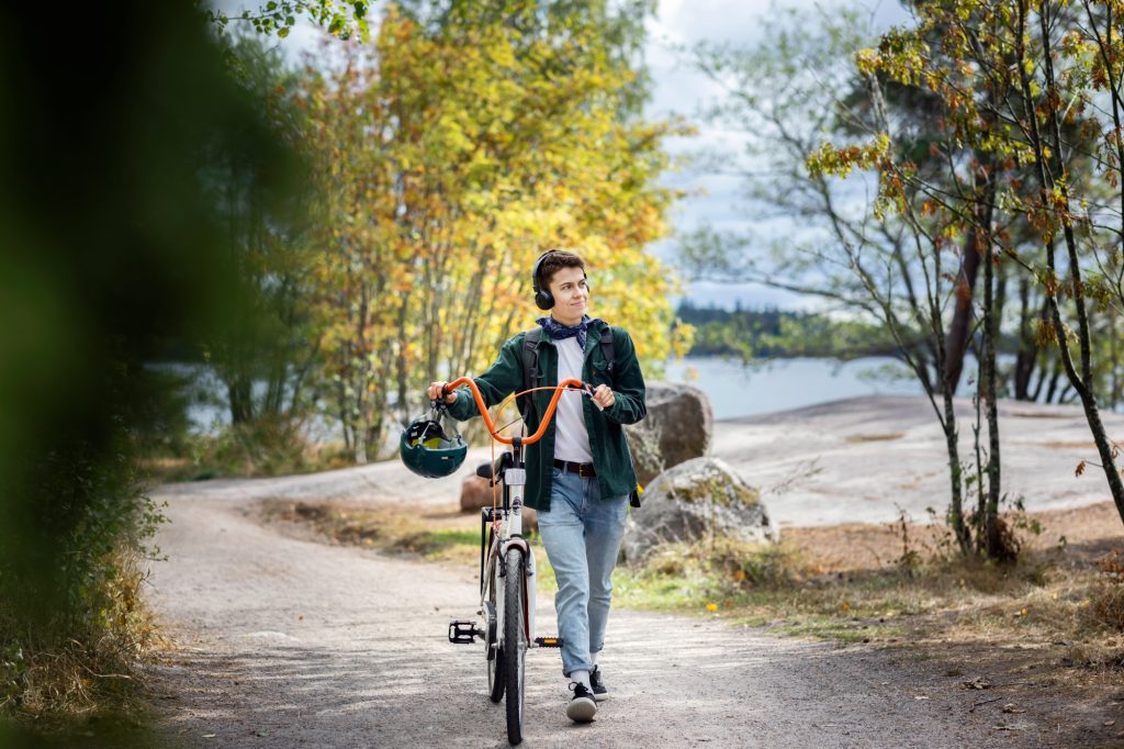 Kuva pyörää taluttavasta miehestä, jolla on päässä kuulokkeet