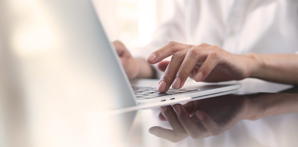 Close-up of a person's hands typing on a laptop keyboard.
